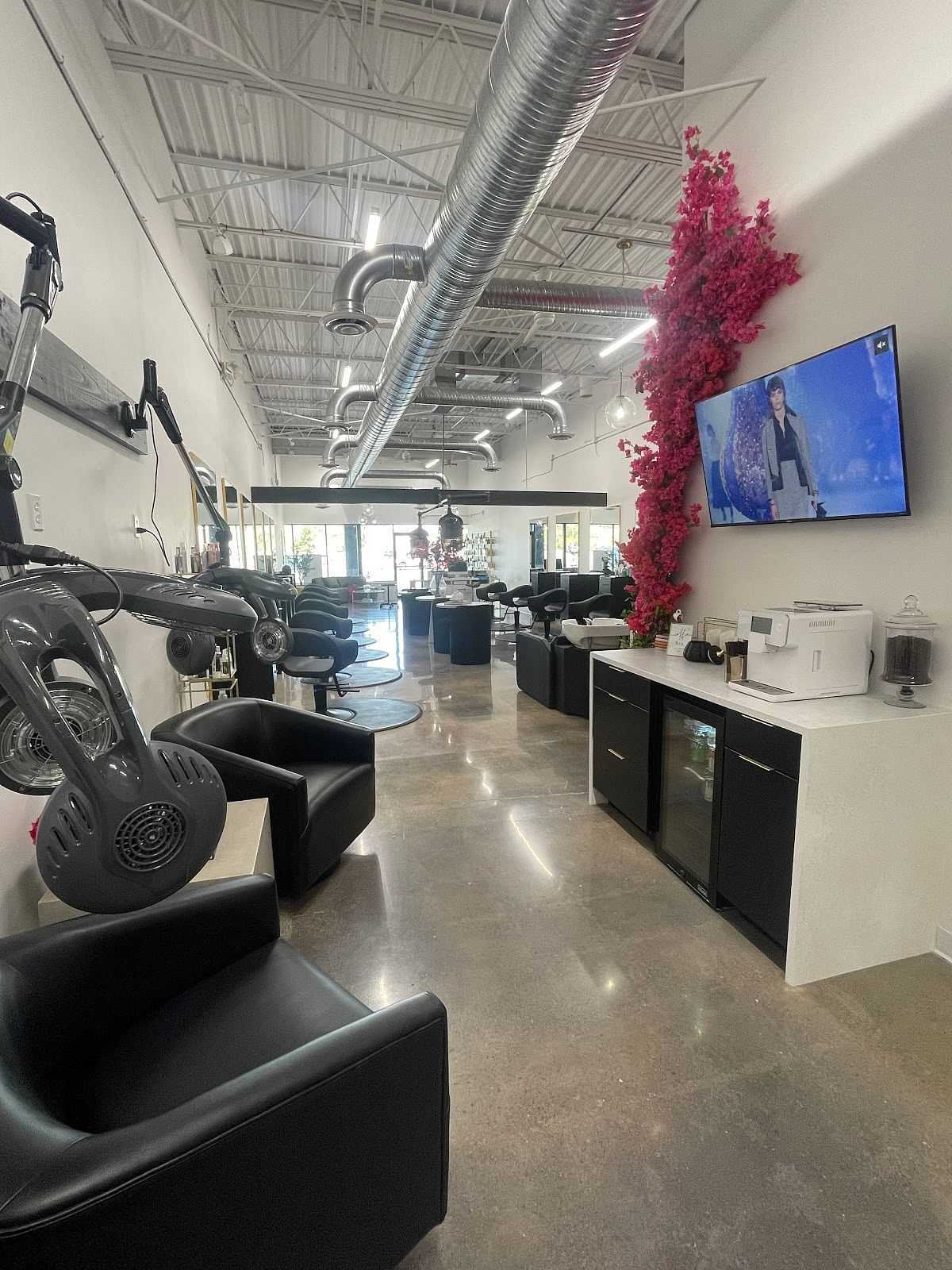 Modern salon interior with styling stations, chairs, and a TV.